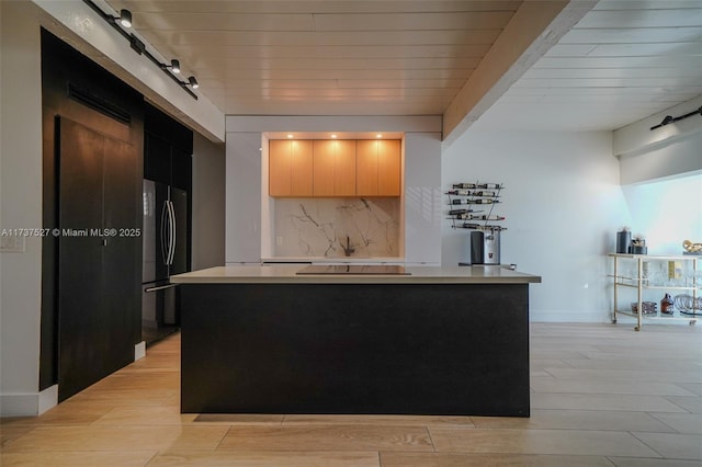 kitchen with light hardwood / wood-style flooring, black appliances, a kitchen island, decorative backsplash, and a barn door