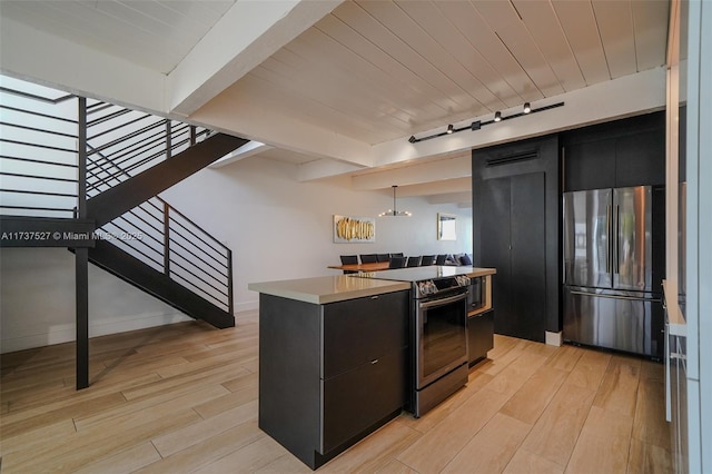 kitchen with light hardwood / wood-style flooring, hanging light fixtures, stainless steel appliances, track lighting, and beamed ceiling