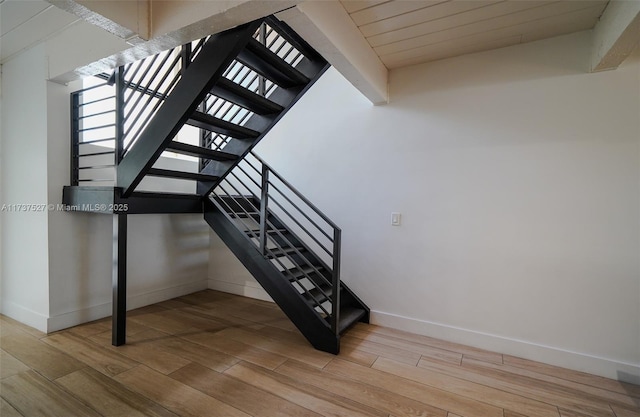 staircase with hardwood / wood-style flooring and beam ceiling