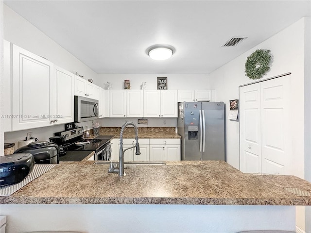 kitchen featuring stainless steel appliances, a peninsula, a sink, visible vents, and white cabinetry