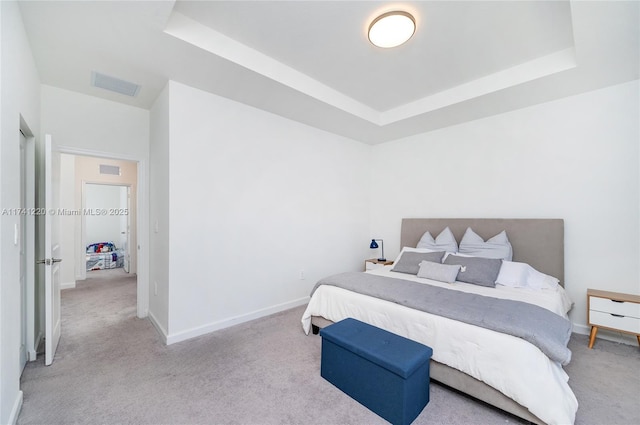 bedroom with a raised ceiling and light carpet