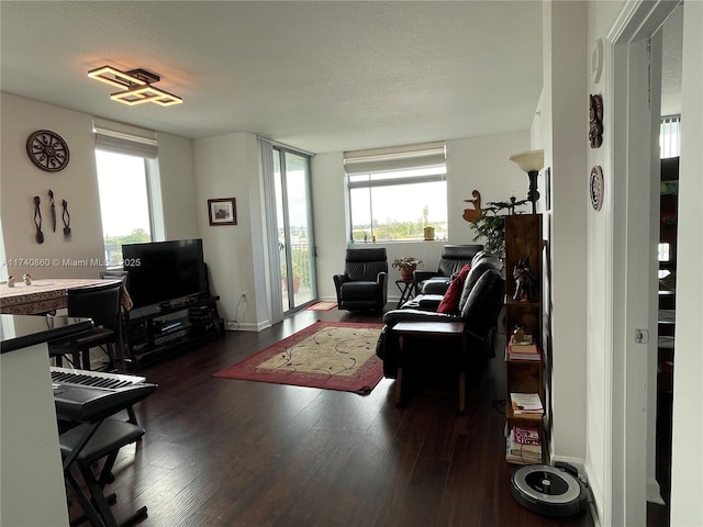 living room with a wealth of natural light, dark wood-type flooring, and a textured ceiling