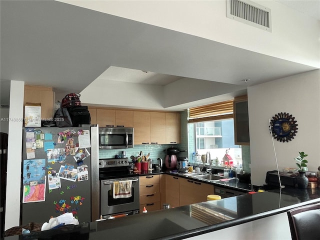 kitchen featuring light brown cabinetry, sink, backsplash, kitchen peninsula, and stainless steel appliances