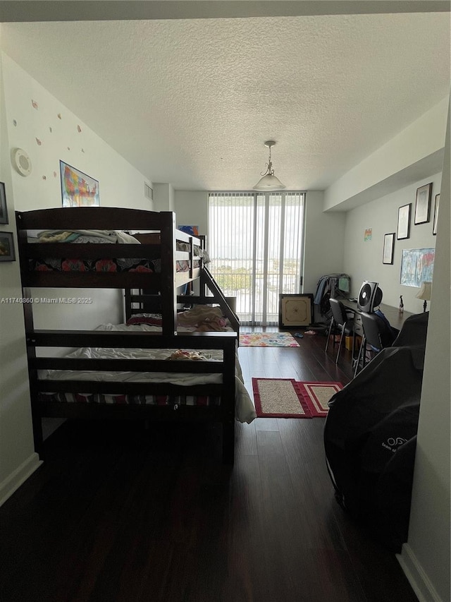 bedroom with hardwood / wood-style flooring, a wall of windows, and a textured ceiling