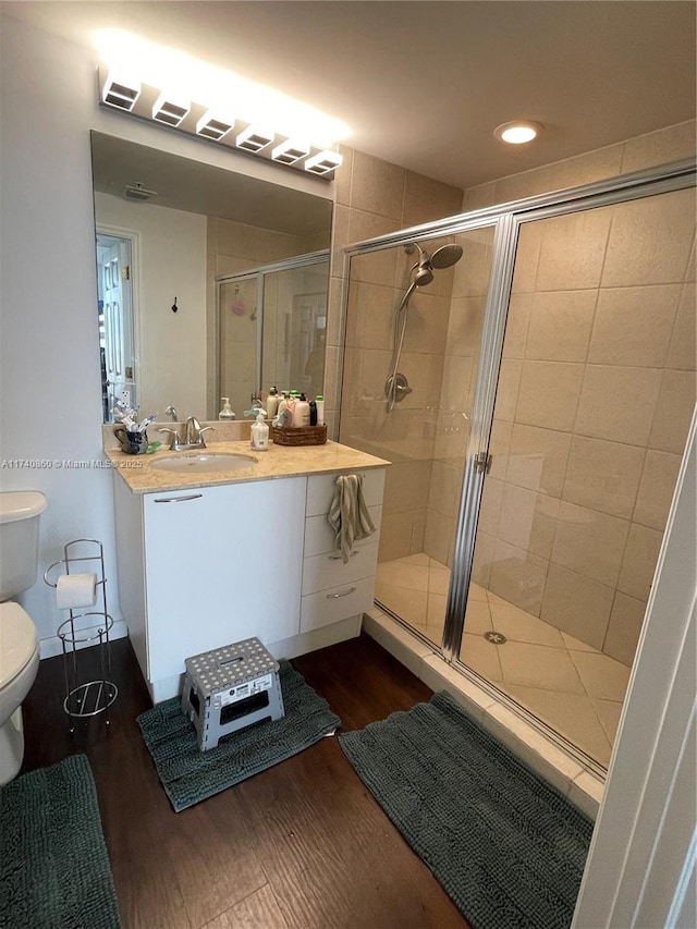 bathroom featuring hardwood / wood-style flooring, vanity, toilet, and a shower with shower door