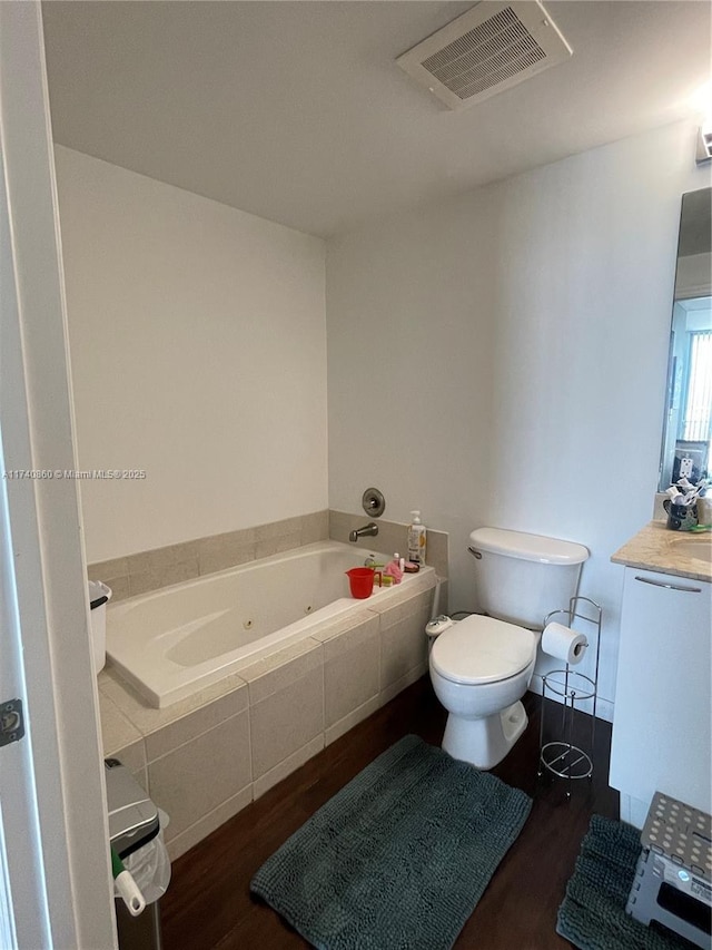 bathroom with tiled tub, vanity, hardwood / wood-style flooring, and toilet