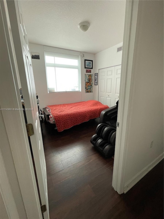 bedroom with dark hardwood / wood-style floors and a textured ceiling