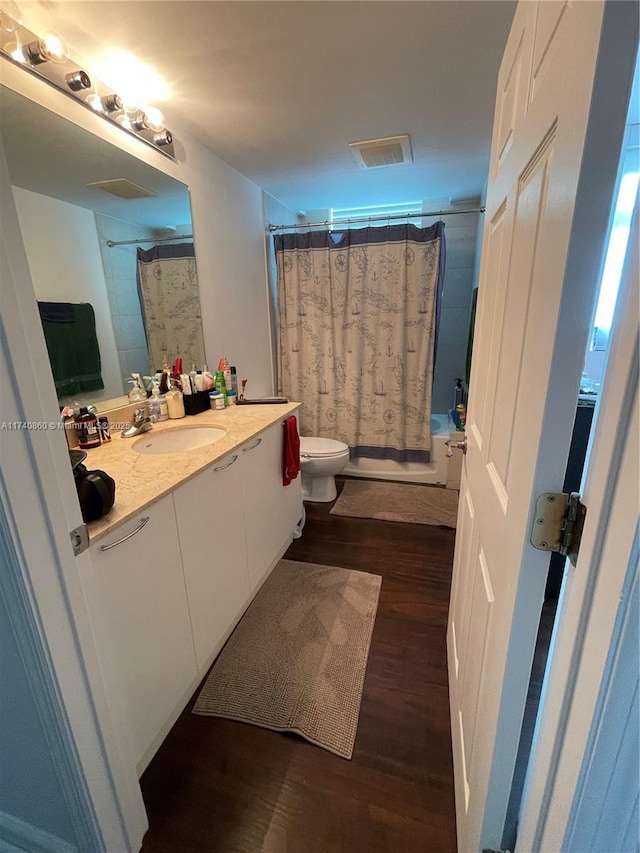 full bathroom with hardwood / wood-style flooring, vanity, toilet, and shower / bath combo with shower curtain