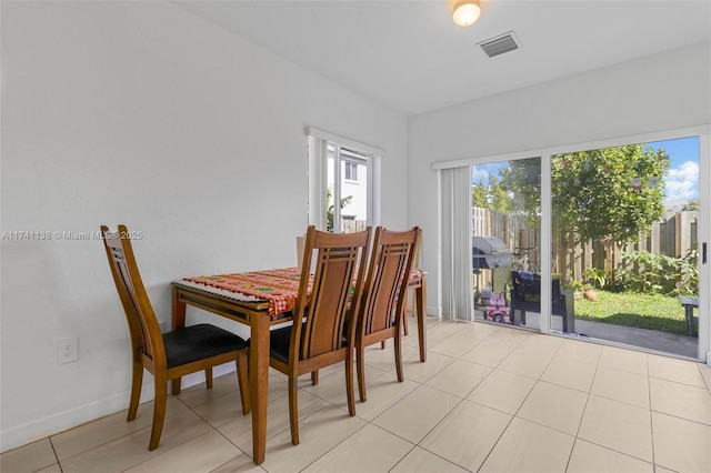 dining space featuring light tile patterned floors, visible vents, and baseboards