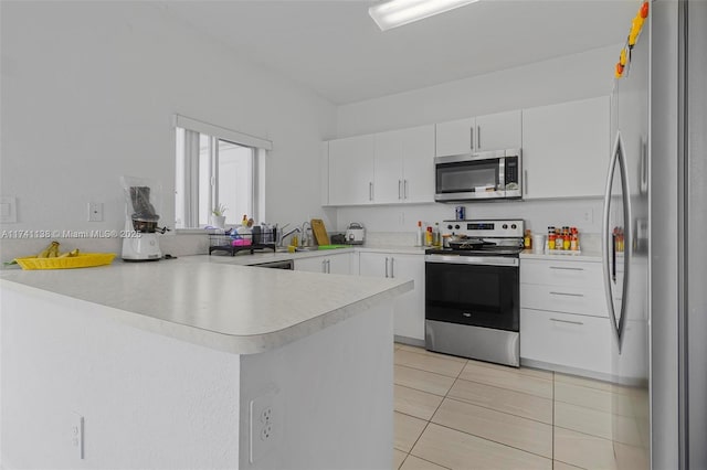 kitchen featuring light tile patterned floors, stainless steel appliances, a peninsula, white cabinets, and light countertops