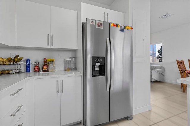 kitchen featuring light countertops, stainless steel refrigerator with ice dispenser, visible vents, and white cabinets