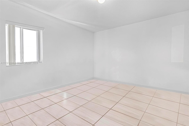 spare room featuring baseboards and light tile patterned floors