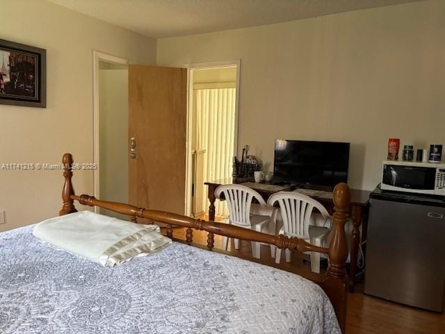 bedroom featuring hardwood / wood-style flooring and stainless steel refrigerator