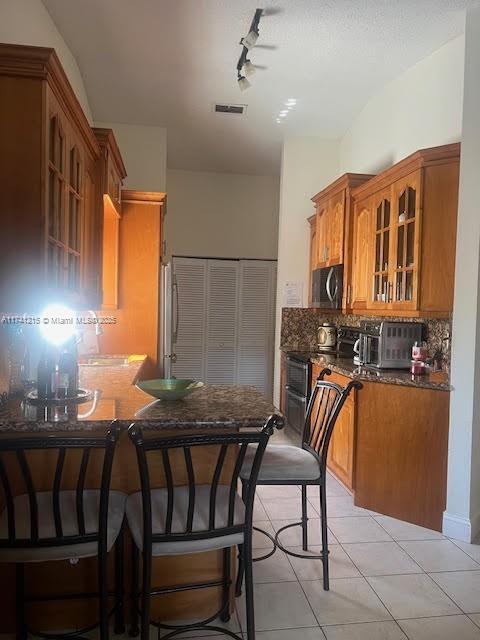 kitchen with tasteful backsplash, a kitchen breakfast bar, light tile patterned floors, kitchen peninsula, and stainless steel appliances