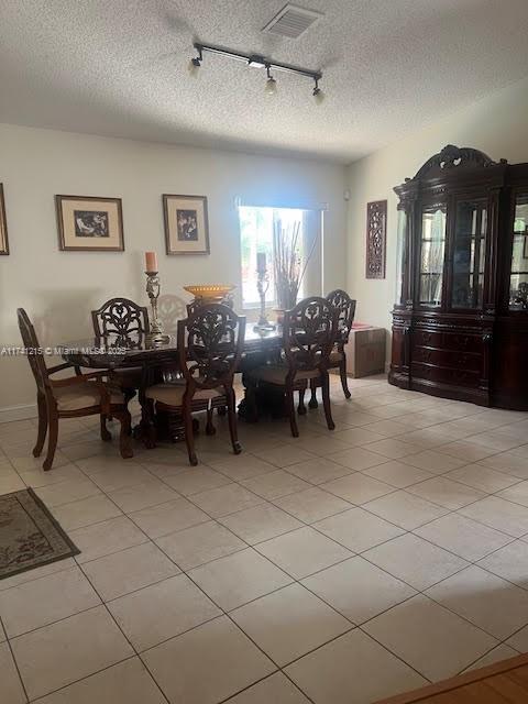 tiled dining area with a textured ceiling