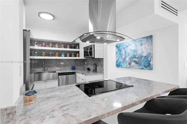 kitchen featuring light stone counters, island range hood, a sink, white cabinetry, and appliances with stainless steel finishes