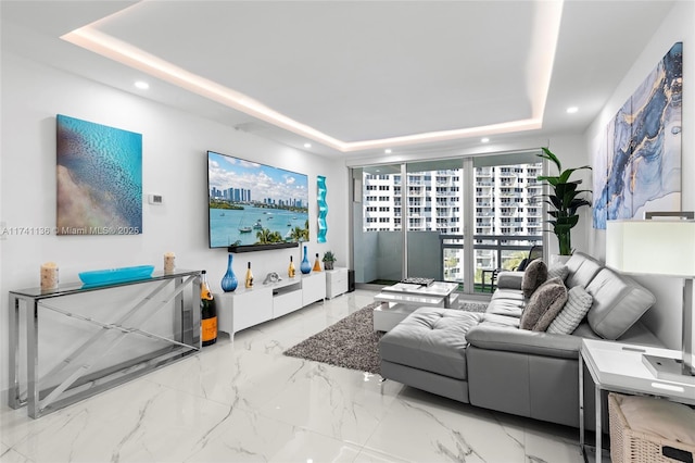 living area featuring marble finish floor, a raised ceiling, and recessed lighting