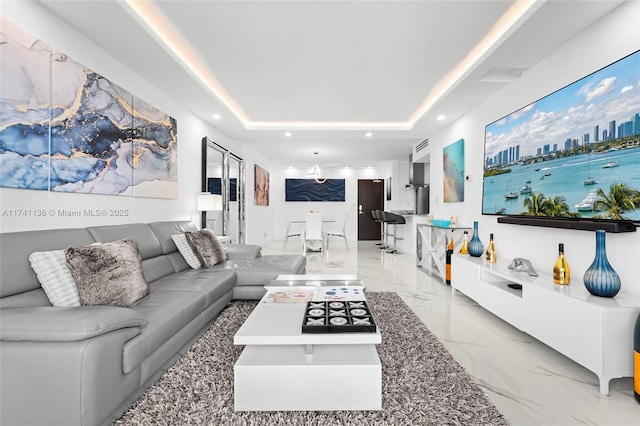 living room featuring marble finish floor, a raised ceiling, and recessed lighting