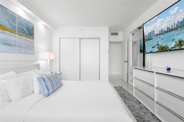 bedroom with a closet, marble finish floor, and visible vents