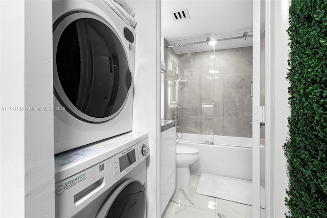 bathroom featuring stacked washer and clothes dryer, marble finish floor, visible vents, toilet, and combined bath / shower with glass door