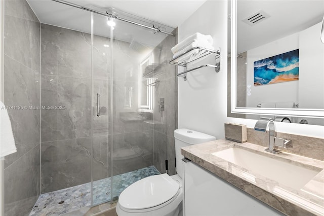 full bathroom featuring visible vents, a shower stall, toilet, and vanity