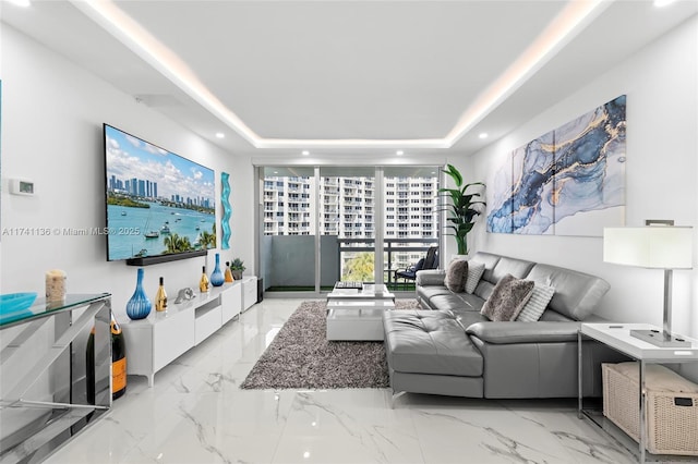 living room with marble finish floor, a tray ceiling, and recessed lighting