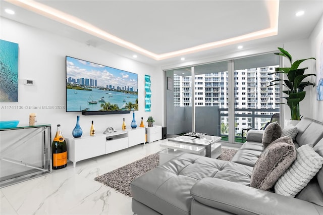 living room with marble finish floor, a tray ceiling, and recessed lighting