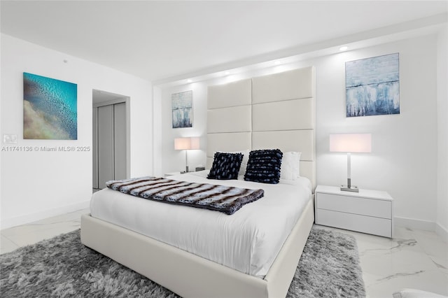 bedroom with marble finish floor, baseboards, and a closet