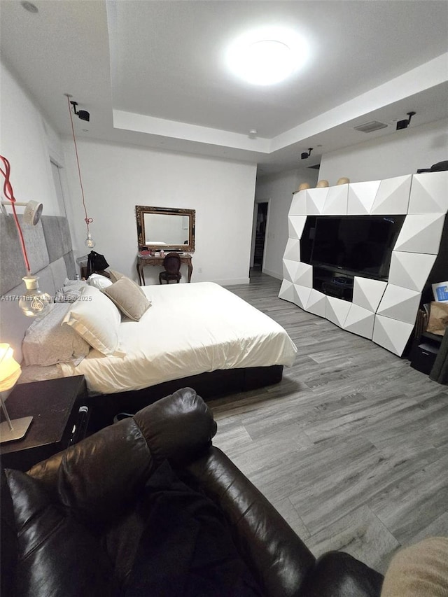 bedroom featuring hardwood / wood-style flooring and a raised ceiling