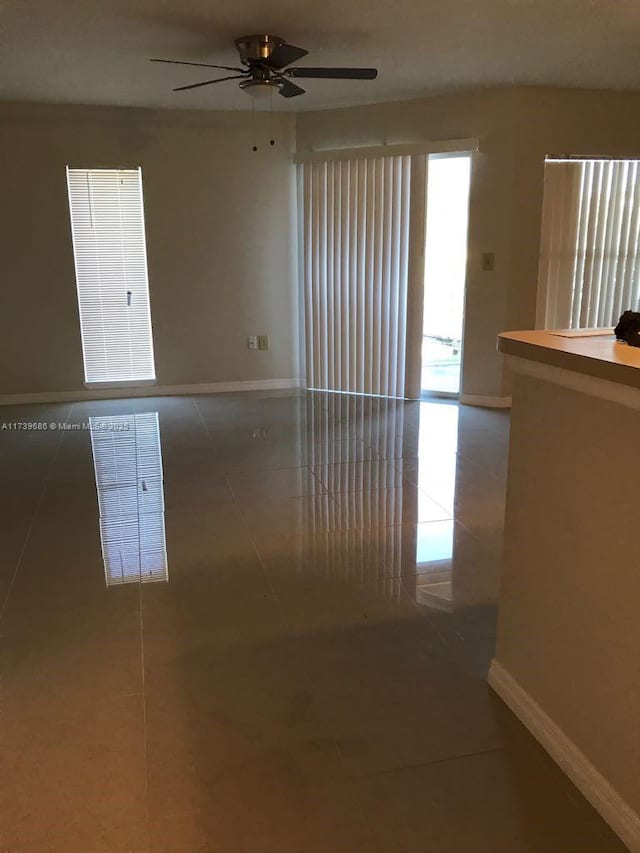 tiled empty room featuring ceiling fan