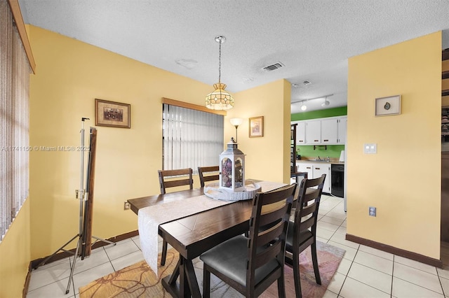 tiled dining room featuring track lighting and a textured ceiling