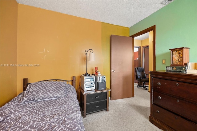 bedroom featuring light colored carpet and a textured ceiling