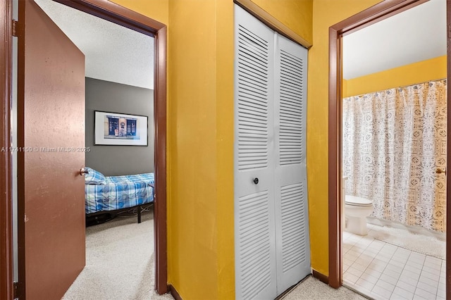 hallway with light carpet and a textured ceiling