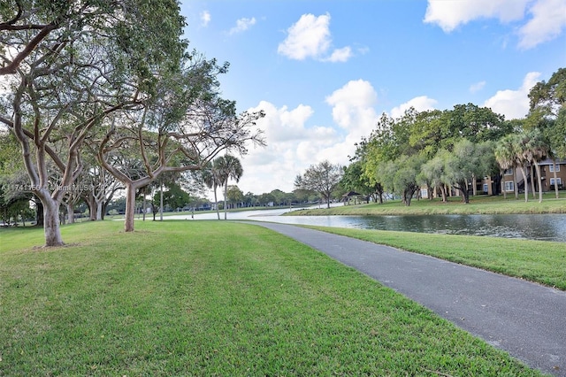 view of home's community with a water view and a lawn