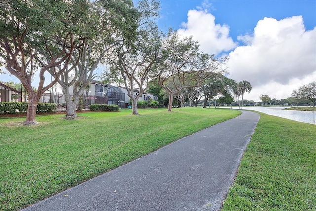 view of property's community with a water view and a lawn