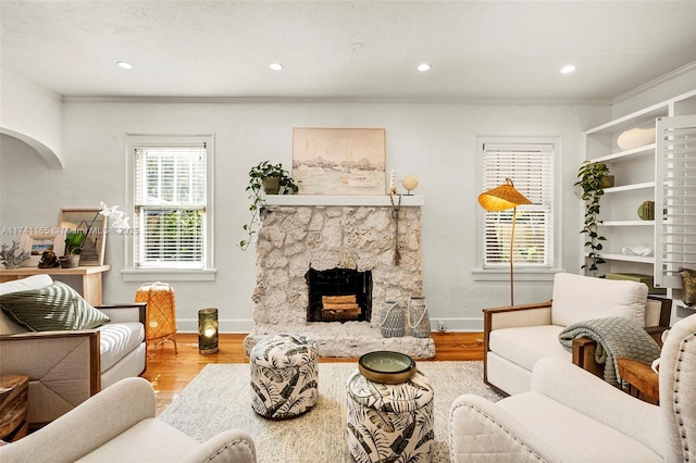 living room featuring a fireplace, crown molding, and light hardwood / wood-style flooring