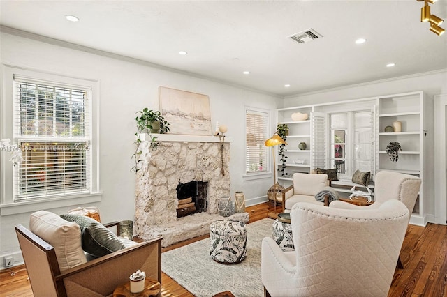 living room featuring ornamental molding, a stone fireplace, and hardwood / wood-style floors