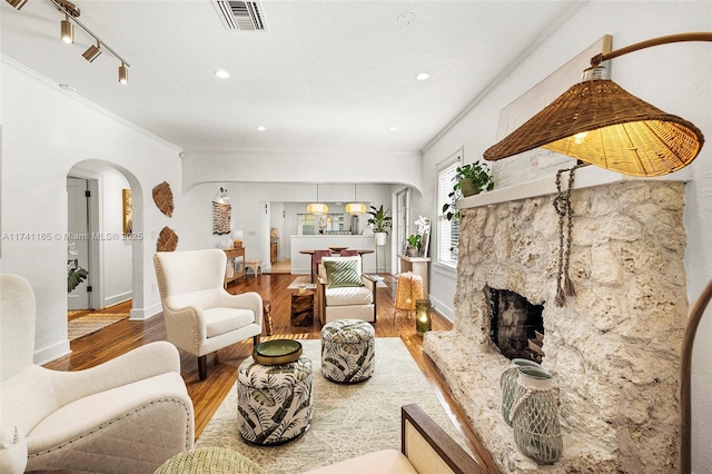 living room with crown molding, hardwood / wood-style floors, track lighting, and a fireplace