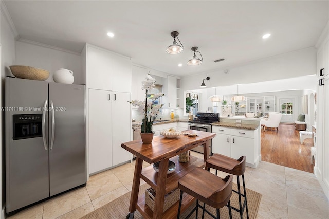 kitchen with pendant lighting, appliances with stainless steel finishes, white cabinetry, ornamental molding, and kitchen peninsula