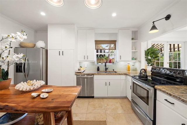 kitchen with sink, white cabinetry, ornamental molding, stainless steel appliances, and light stone countertops