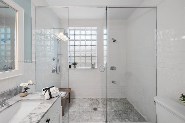 bathroom featuring toilet, tile walls, vanity, and walk in shower