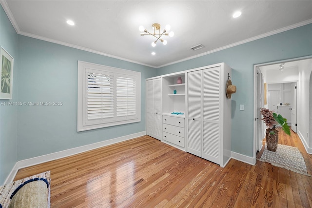 bedroom featuring hardwood / wood-style floors, crown molding, a closet, and a chandelier