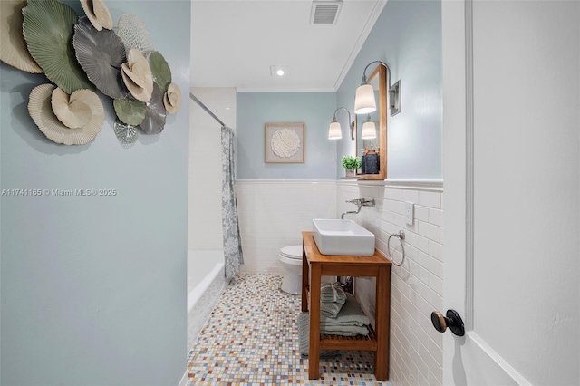 full bathroom with shower / tub combo with curtain, toilet, tile walls, ornamental molding, and vanity