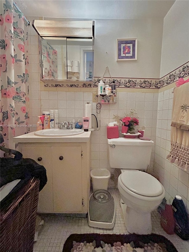 bathroom with tile walls, vanity, and toilet