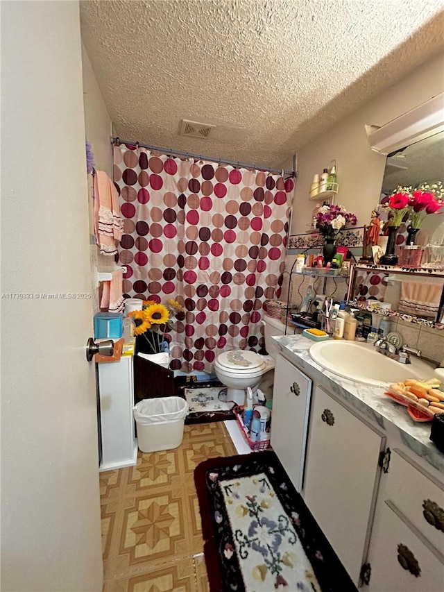 bathroom with a shower with curtain, vanity, a textured ceiling, and toilet