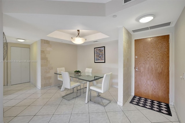 unfurnished dining area with a raised ceiling and light tile patterned floors