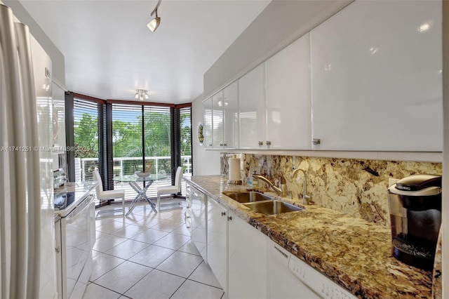 kitchen featuring sink, stone countertops, light tile patterned floors, white appliances, and white cabinets