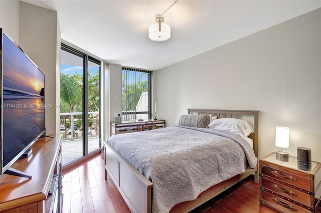 bedroom with expansive windows, access to outside, and dark hardwood / wood-style flooring