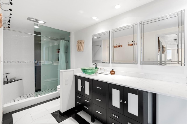 bathroom with vanity, a shower with shower door, tile patterned floors, and toilet