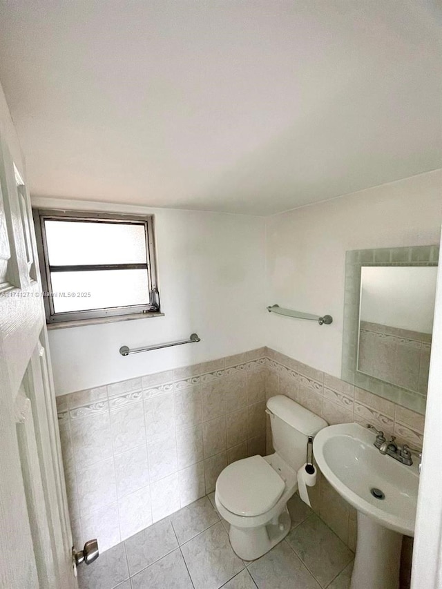 bathroom with tile patterned floors, toilet, sink, and tile walls